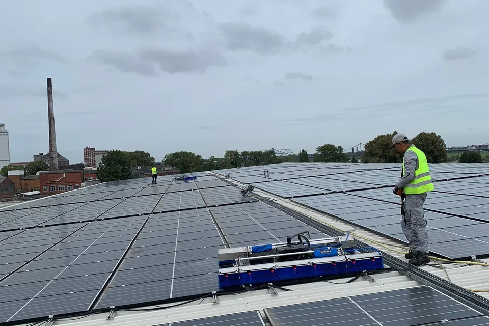 Reinigungsroboter und Mitarbeiter auf einer PV-Dachanlage